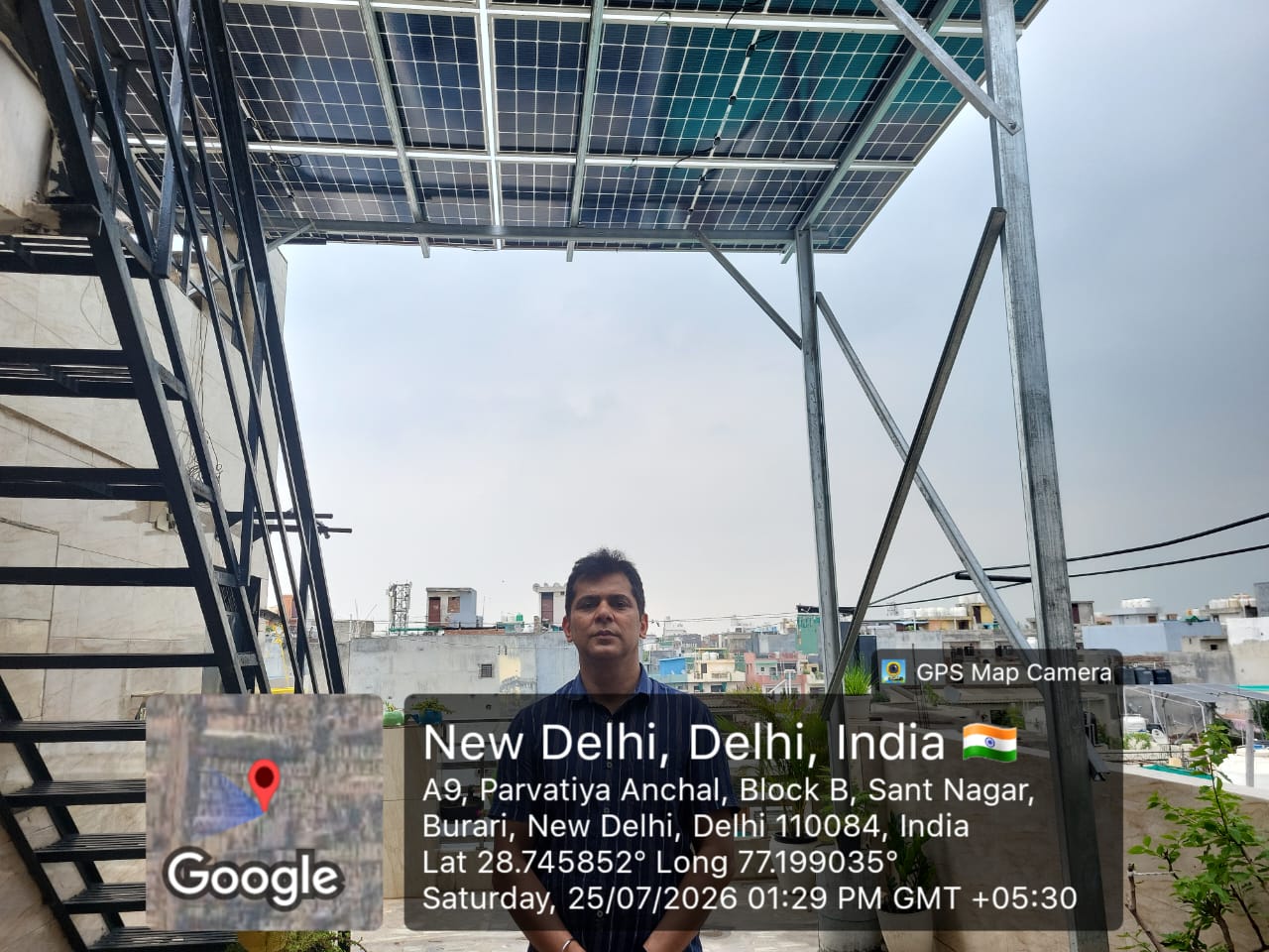 A person standing beneath elevated rooftop solar panels beside a metal staircase